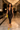 Woman walking through a luxury hotel lobby wearing a black lace halter capri romper with yellow heels and matching clutch for an elegant evening look.