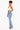 A woman modeling light-wash blue flare jeans with a white crop top, standing against a plain white studio background.
