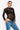Person wearing a black lace long-sleeve top and blue jeans on a white background