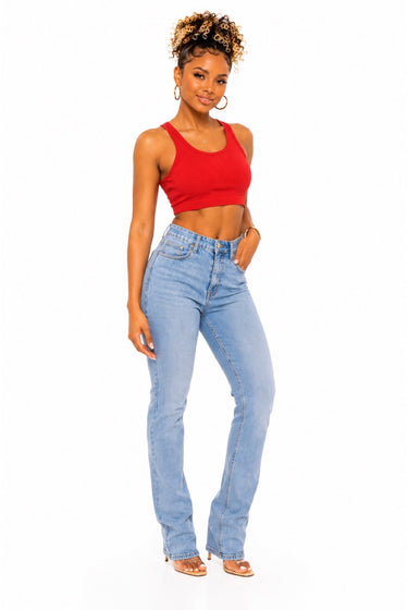 A woman modeling a red ribbed crop top and light-wash blue high-rise flare jeans against a plain white background.
