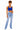 A woman modeling a royal blue crop top and light-wash blue jeans with blue and white sneakers, standing against a plain white background.