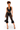 A model wearing a black satin halter crop top and black lace cropped pants with ruffled hems, holding a small black handbag against a plain white background.