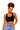 A woman with curly hair wearing a black scoop-neck crop top and light blue jeans, posing against a solid white background.