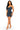 A woman modeling a fitted mini dress made from dark blue denim panels with contrast black denim trim and a central zipper detail, paired with clear high-heel sandals, against a plain white background.