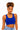A woman wearing a bright royal blue scoop-neck crop top and light-wash blue jeans, photographed against a plain white studio background.