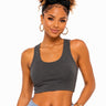 A woman modeling a dark gray scoop-neck crop top with light blue jeans against a plain white background.