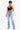 A woman modeling a pair of light-wash blue high-rise flare jeans with a black crop top, standing against a plain white studio background.